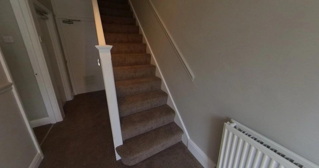 Carpeted staircase and hallway with neutral wal...