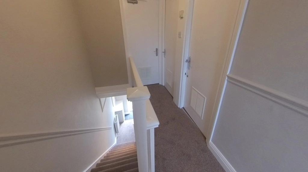 Bright neutral upstairs hallway with carpeted f...