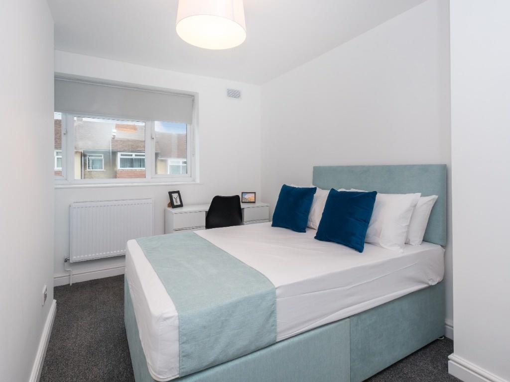 Bright, modern double bedroom with a padded hea...