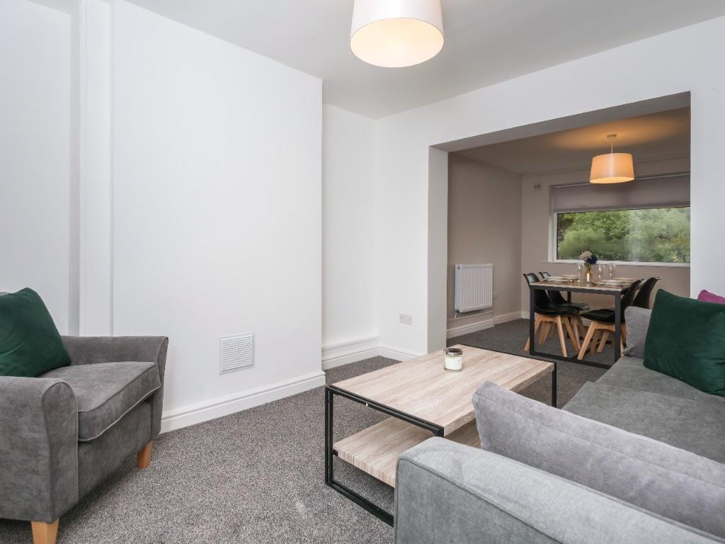 Bright, modern living room with grey sofas, a c...