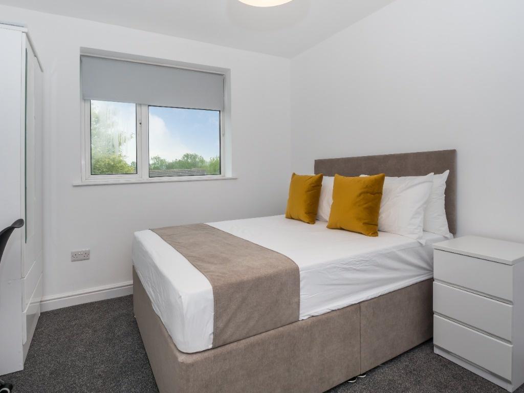 Bright, simply styled double bedroom with a com...
