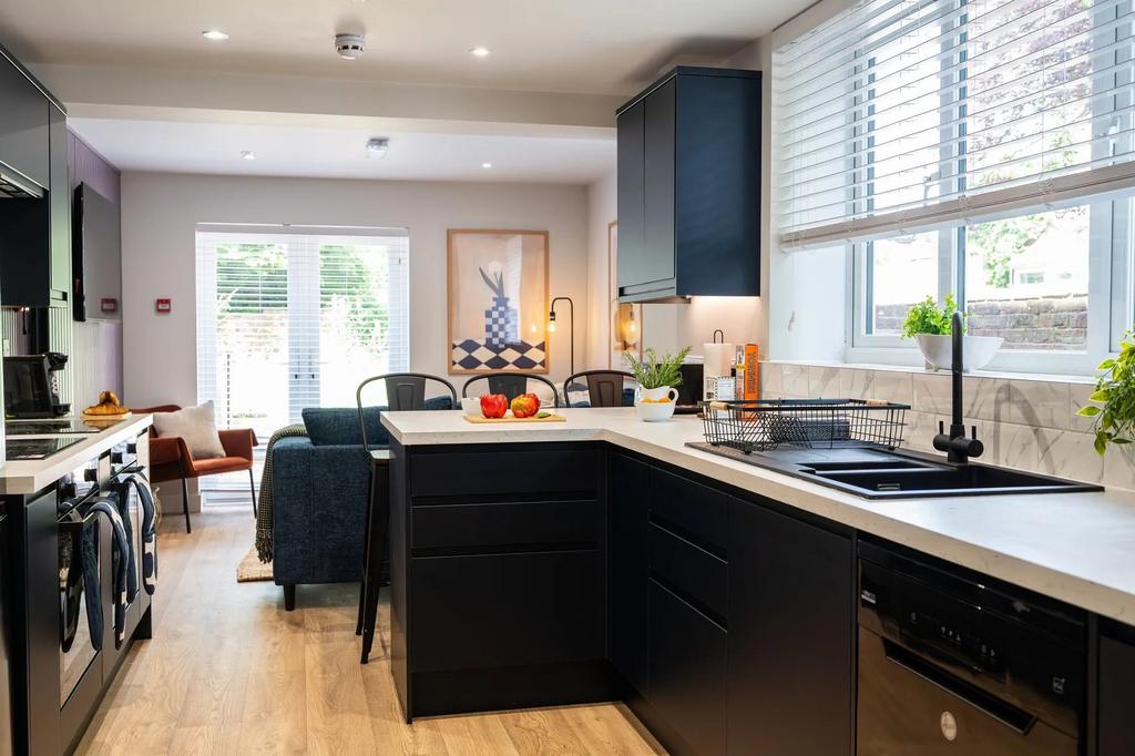 Modern kitchen with sleek dark cabinetry, brigh...