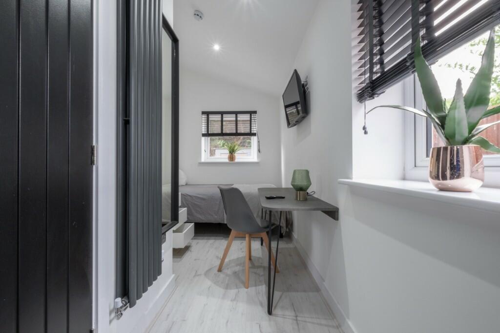 A modern and tidy single bedroom featuring a sl...