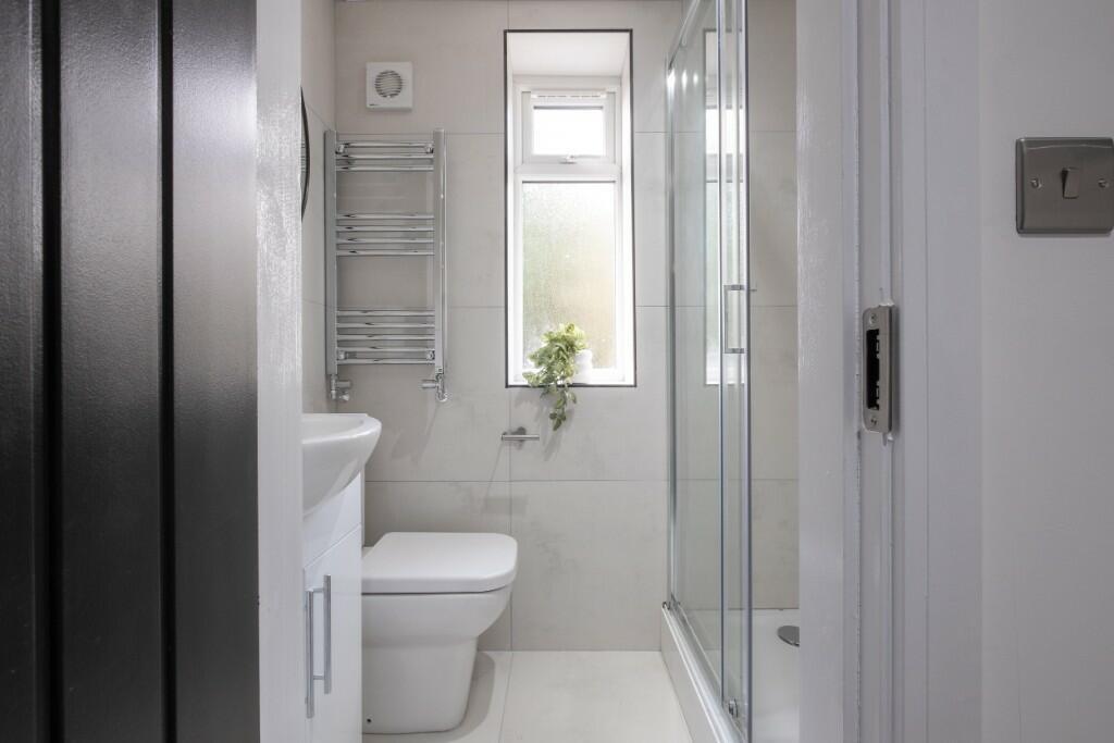 A bright, modern bathroom featuring a glass-enc...