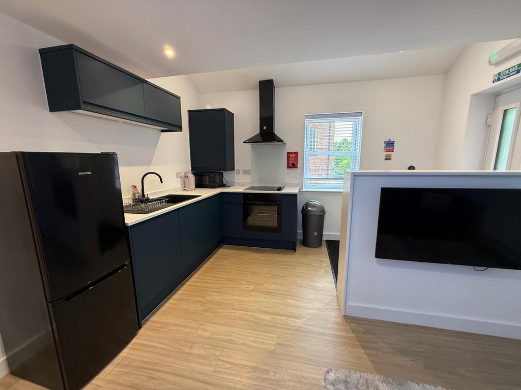 Modern L-shaped kitchen with dark cabinetry, in...