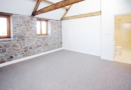 Bright master bedroom with exposed stone wall a...