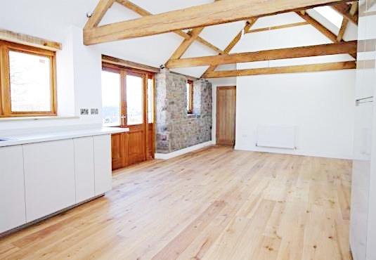 Bright open-plan living area with exposed woode...