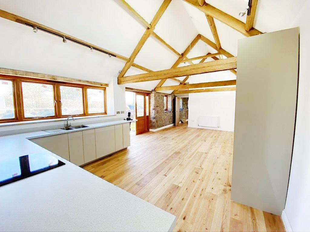 Bright, open-plan living space with exposed tim...