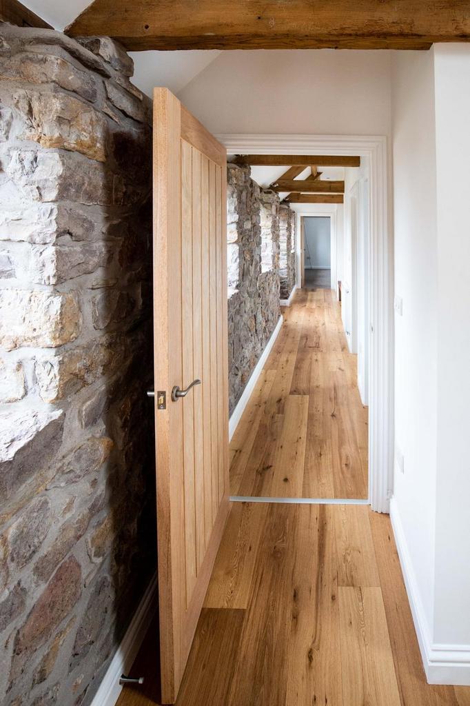 Bright, stylish hallway with exposed stone wall...