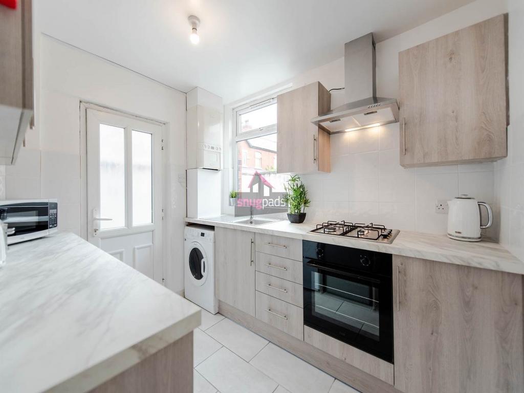 Bright modern galley kitchen with light wood ca...