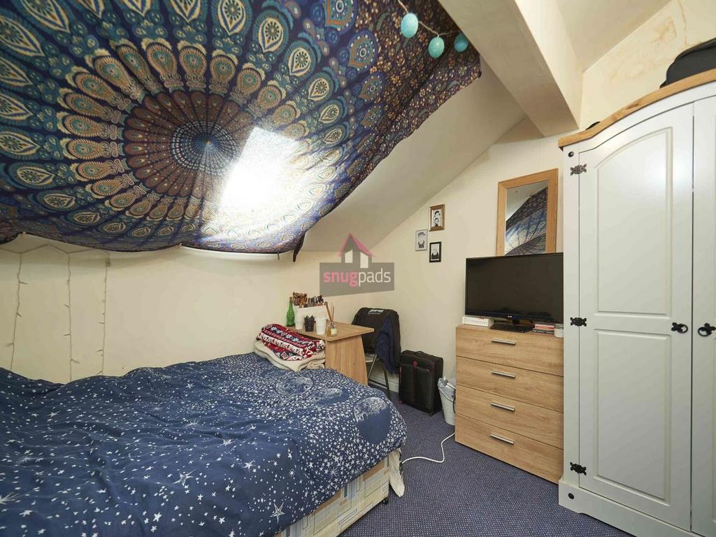 Cozy double bedroom under a sloped ceiling with...