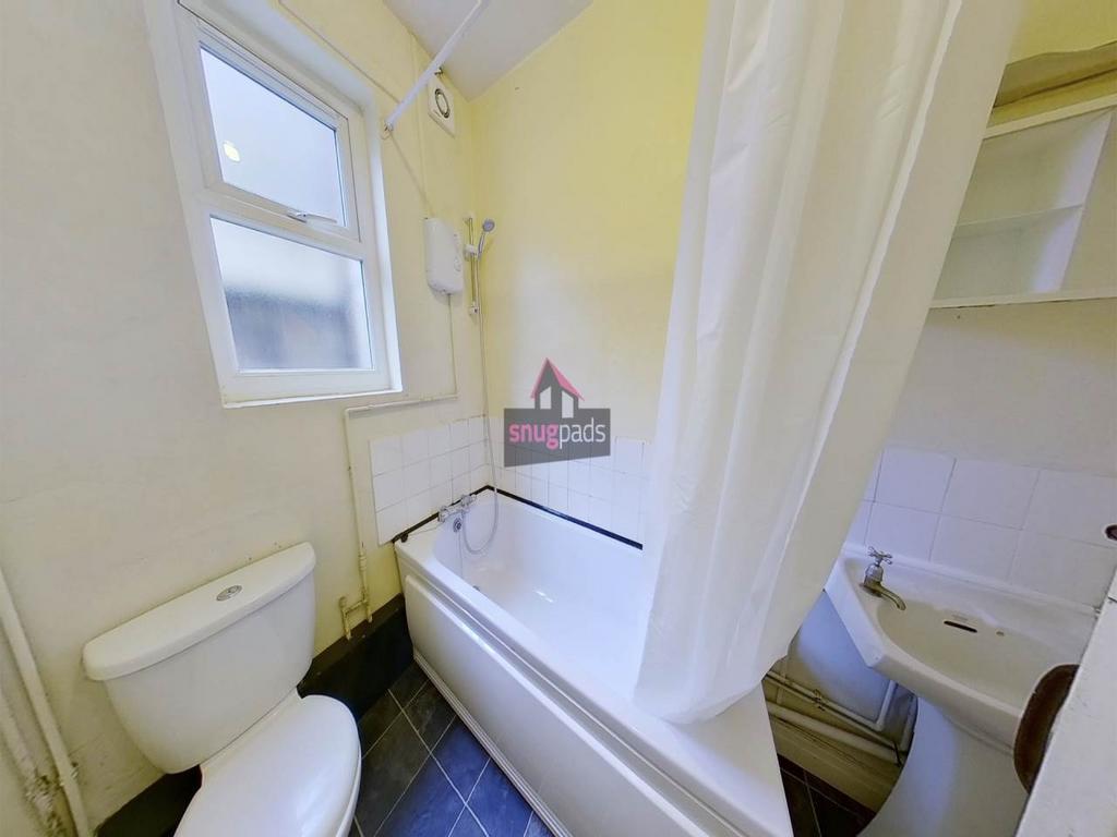Bright bathroom with a white bathtub and shower...