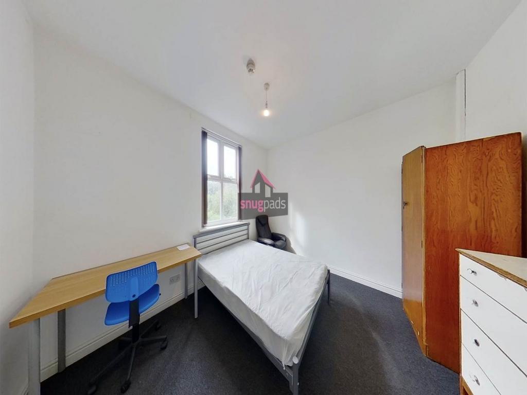 Bright, simply furnished bedroom with a desk by...