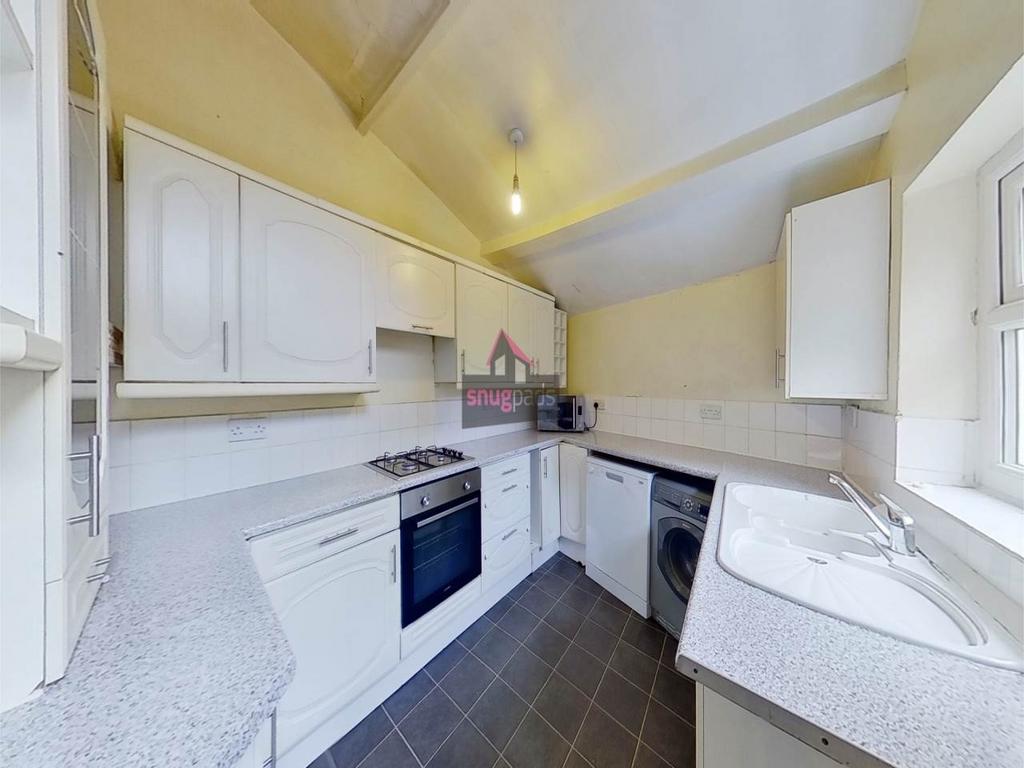 Bright, modern kitchen with white cabinetry, in...