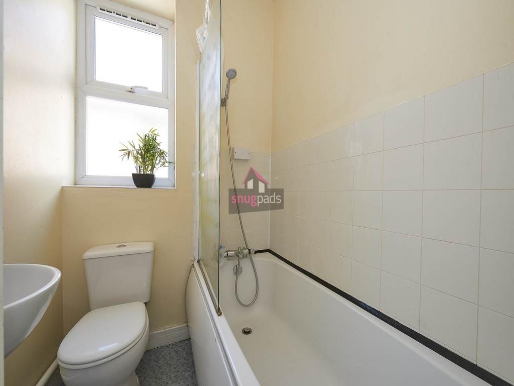 Bright bathroom featuring a bathtub with overhe...