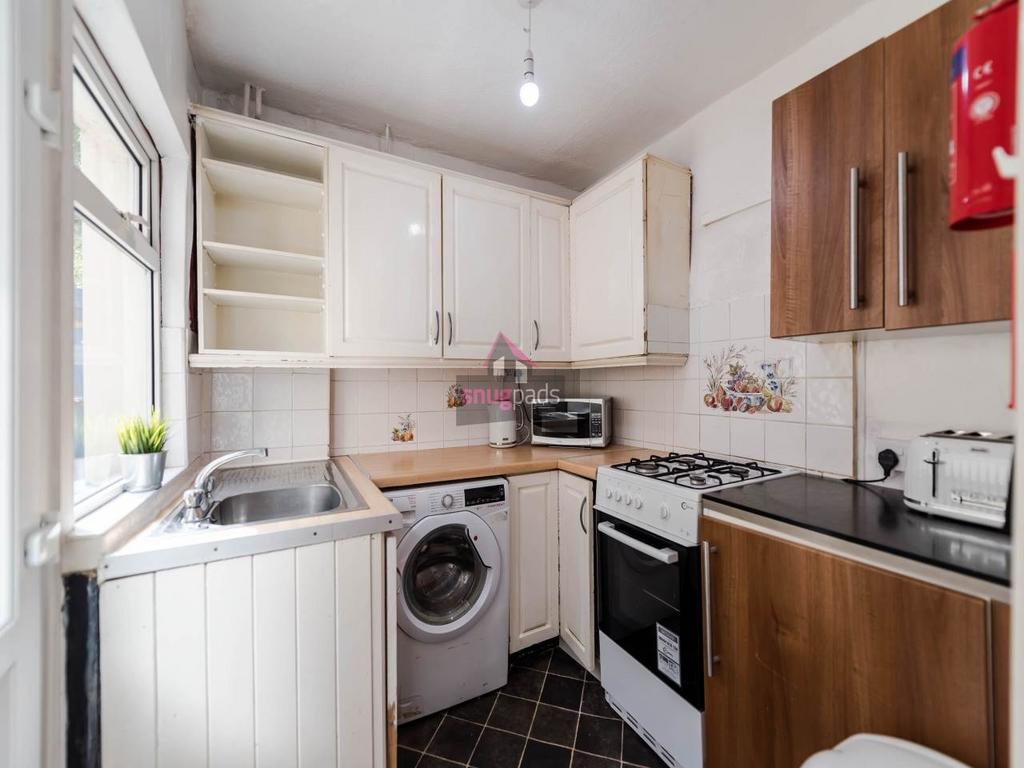 Bright compact kitchen with white cabinetry, a ...