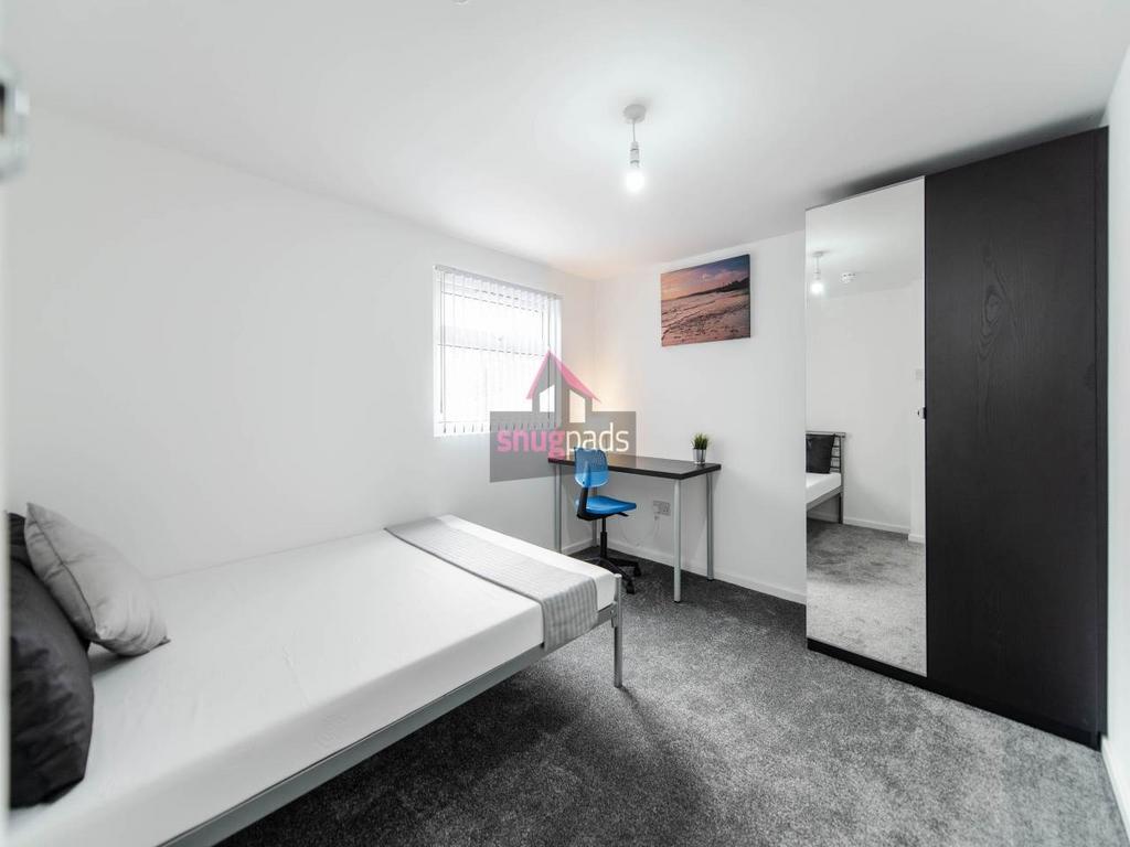 Bright, simply furnished bedroom with a comfort...