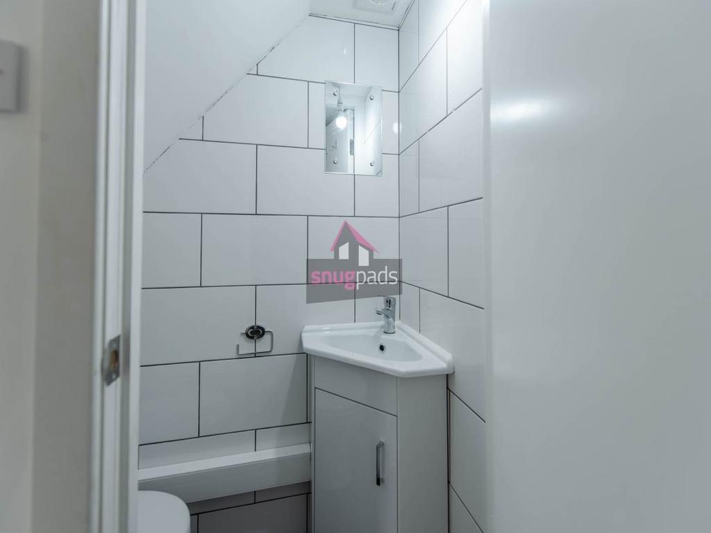 Compact modern bathroom with white tiled walls,...