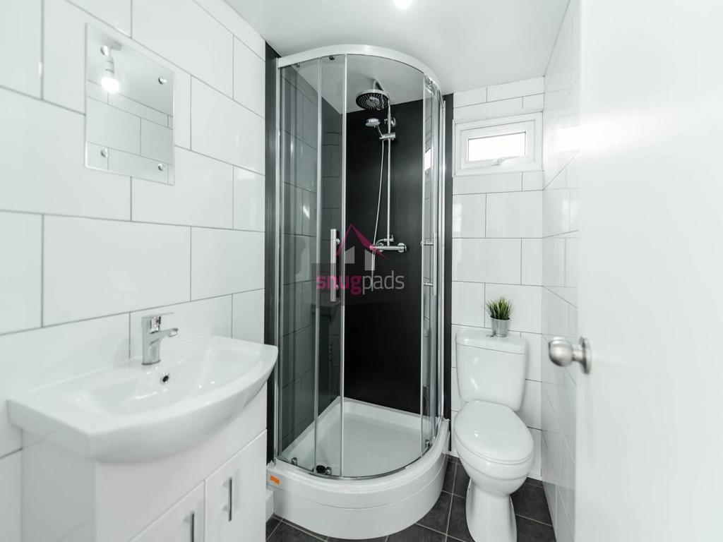 Bright, modern bathroom with a curved glass sho...