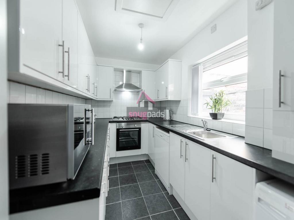 Bright, modern galley kitchen with white cabine...