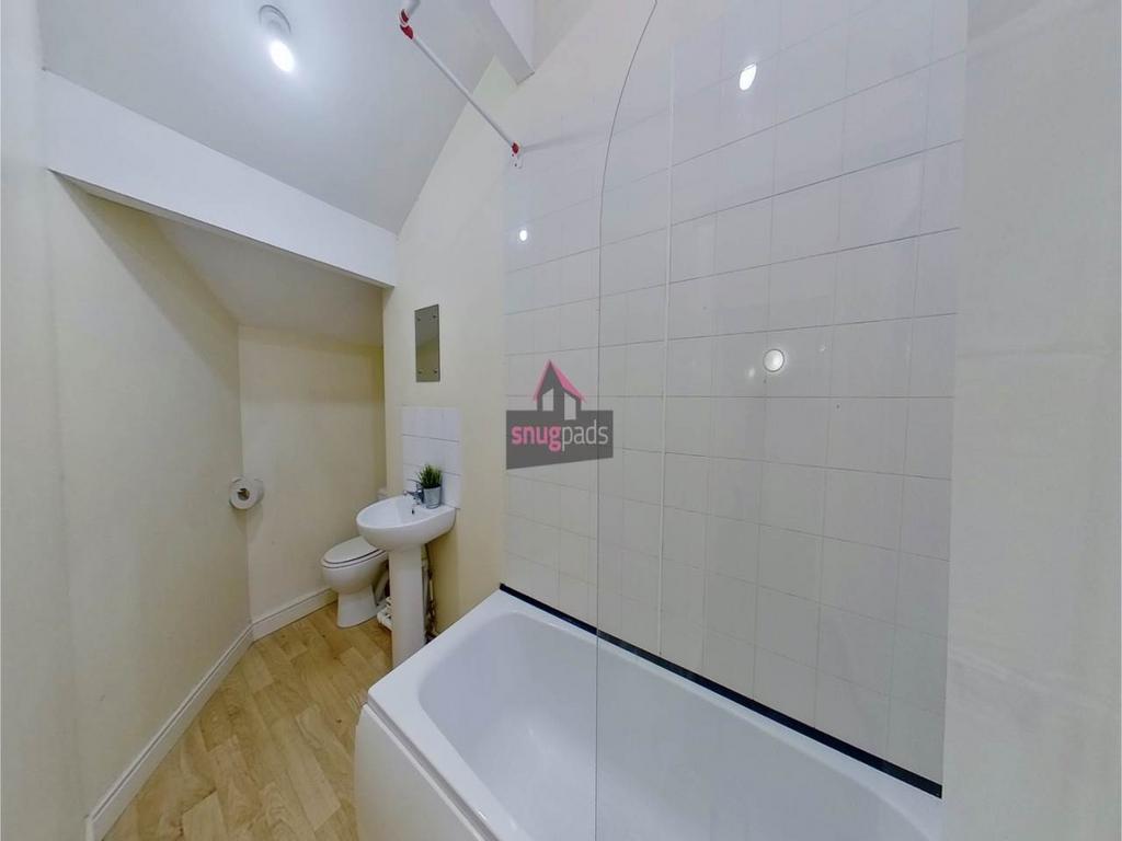 Bright, clean bathroom featuring a bath with gl...
