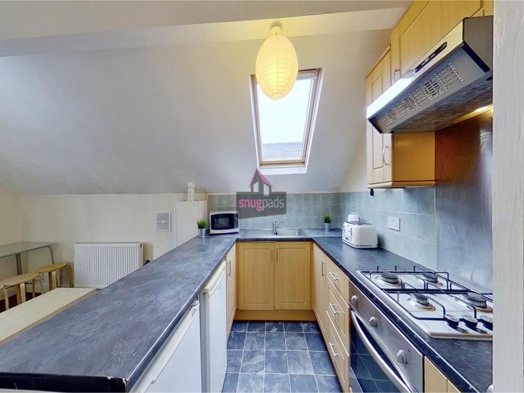 Bright fitted kitchen with sloped ceiling and s...