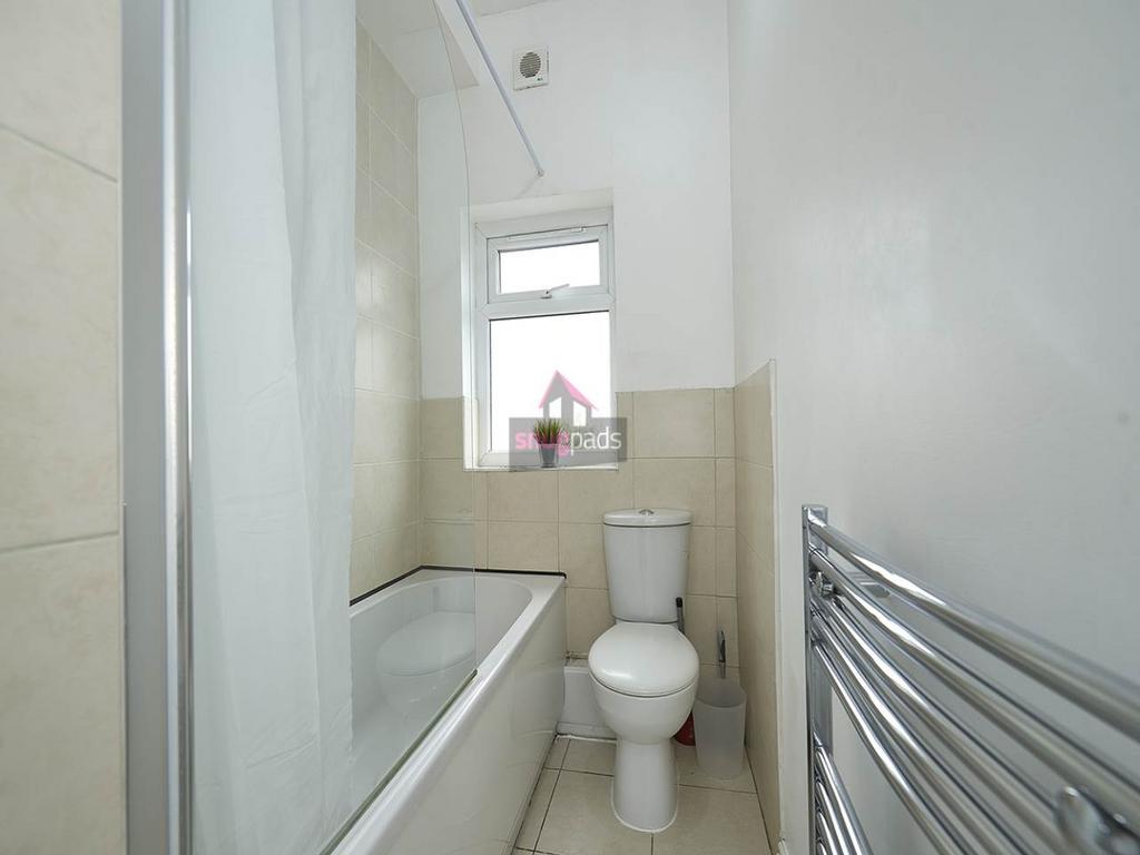 Bright, tiled bathroom with a bath and shower s...
