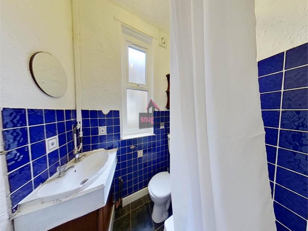 Bright bathroom with bold blue tiled walls, a w...