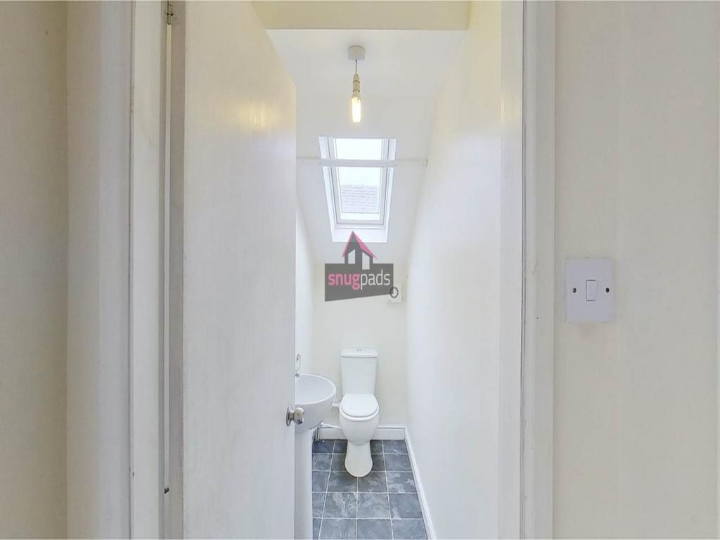 Bright, narrow WC with a clean white suite, sky...