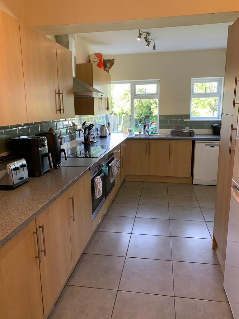 Bright galley-style kitchen with light wood cab...