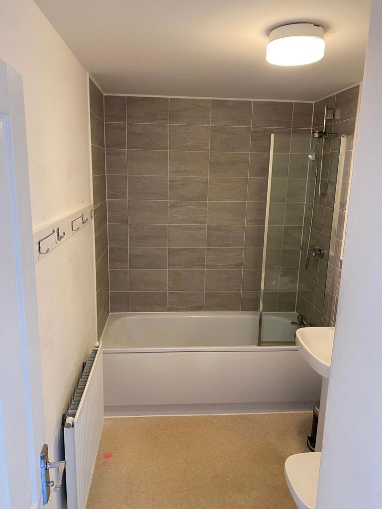 A clean, modern bathroom featuring a bathtub wi...
