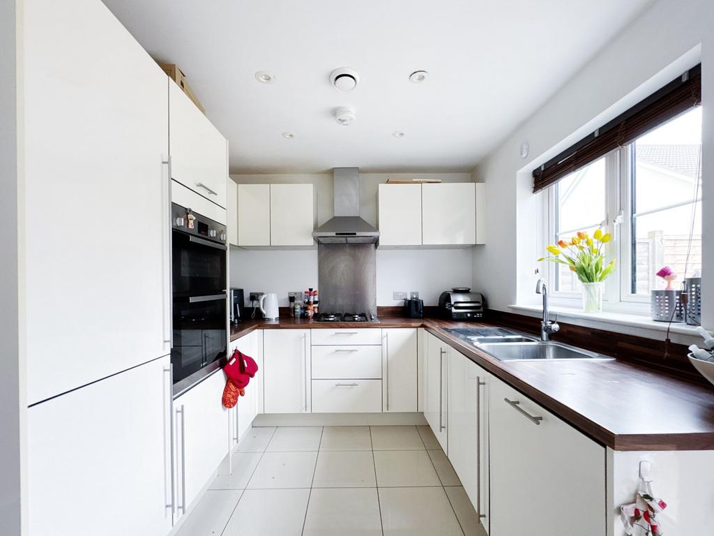 Bright modern kitchen with white cabinetry, dar...