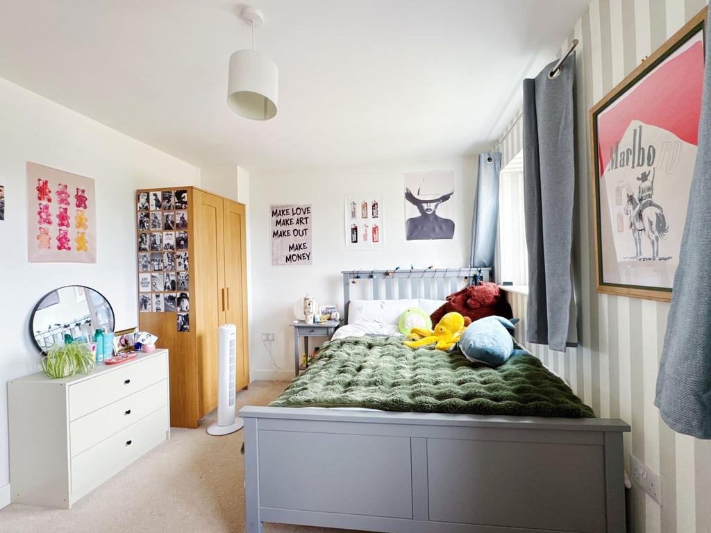 Bright, neatly styled bedroom with a painted be...