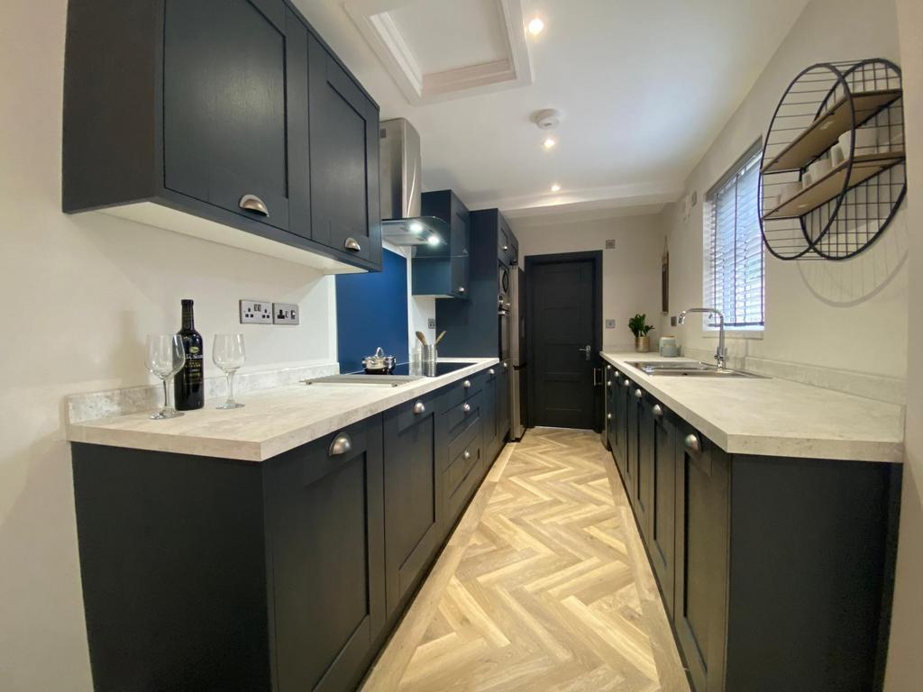 Modern galley kitchen with dark cabinetry, ligh...