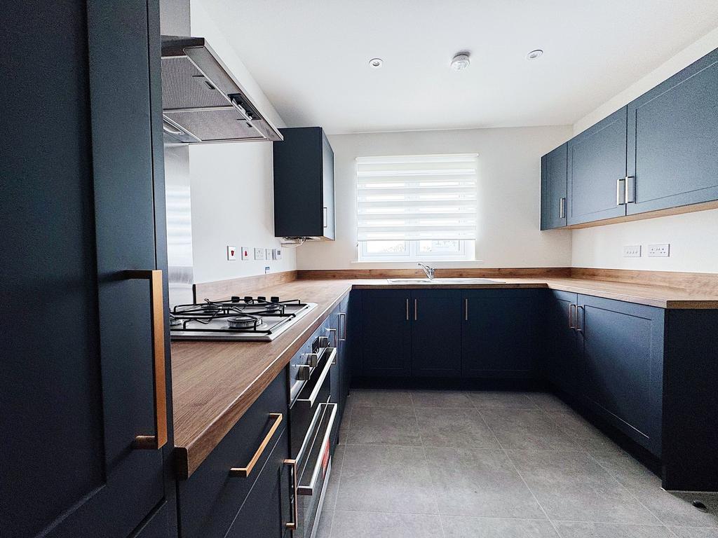 Modern L-shaped kitchen with dark cabinetry, wo...
