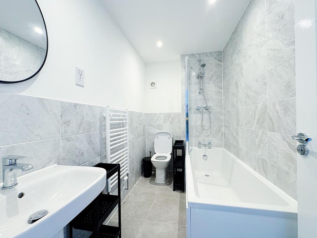 Bright, modern bathroom with a full bathtub and...