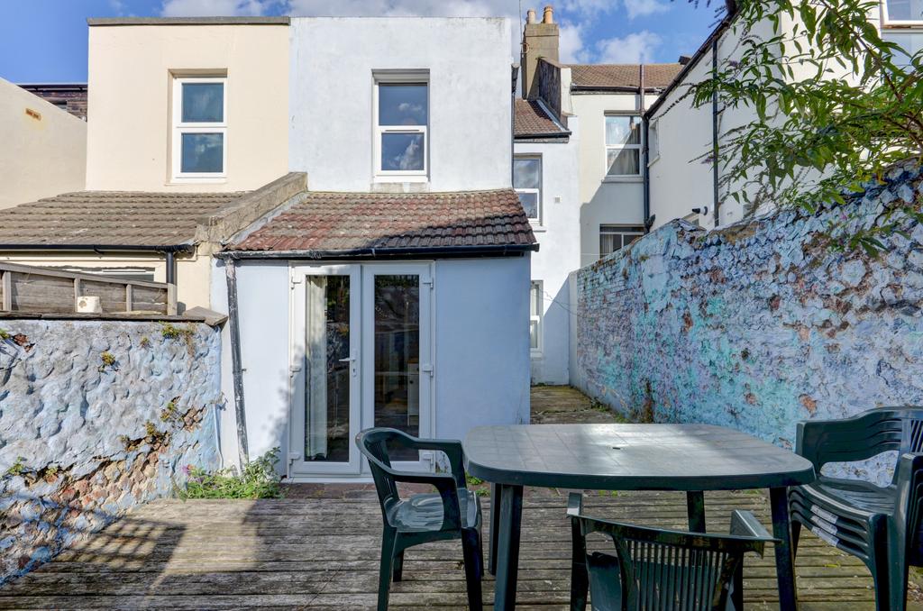 Sunny paved rear garden with a patio dining tab...
