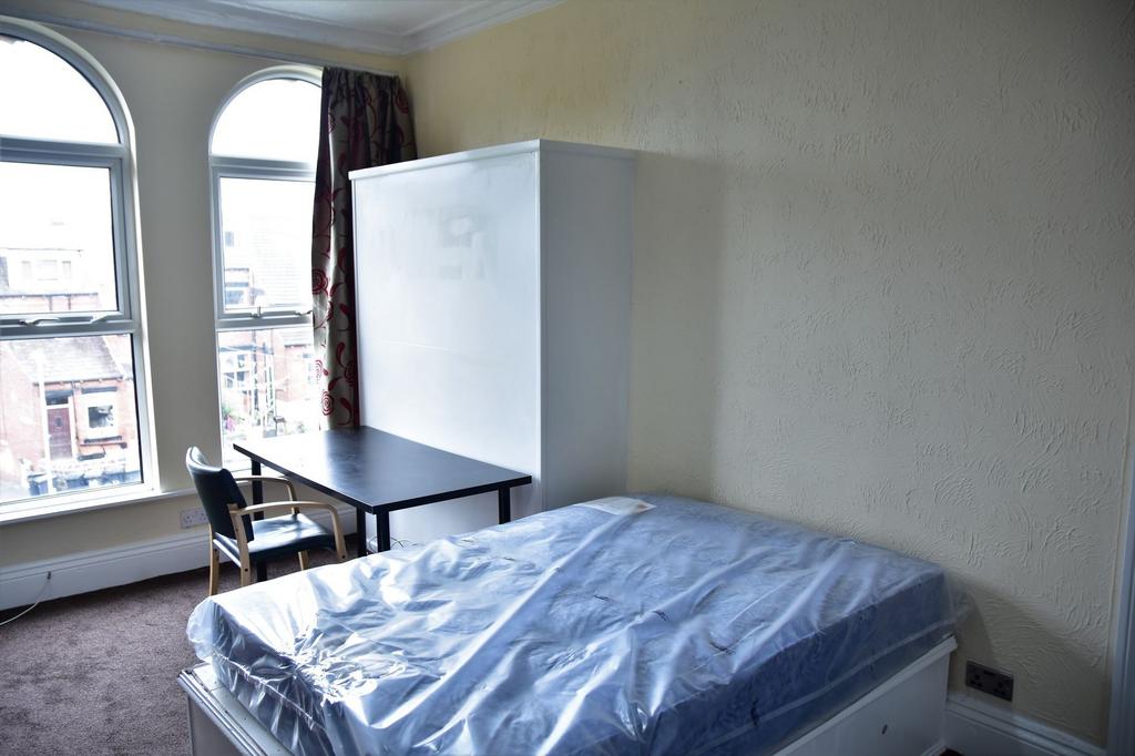 A cozy single bedroom featuring a large window ...