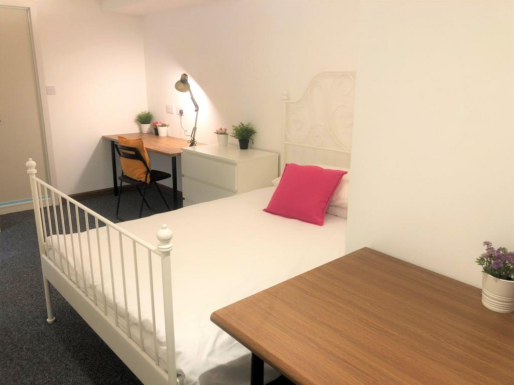 A neat and cozy single bedroom featuring a whit...