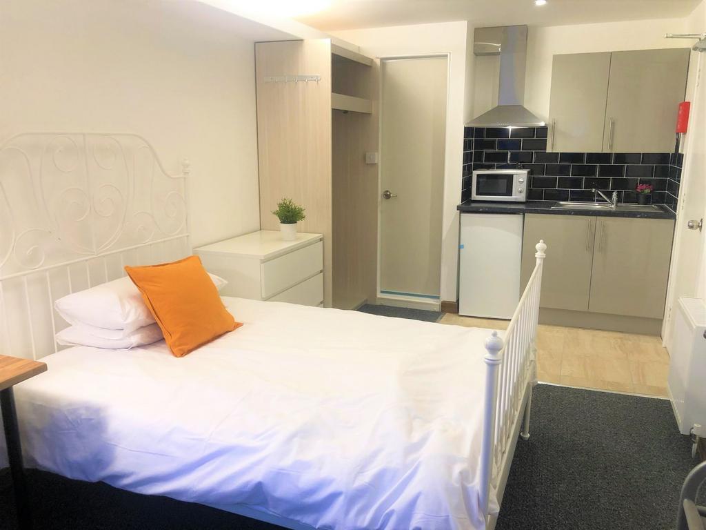 A clean and cozy single bedroom featuring a whi...