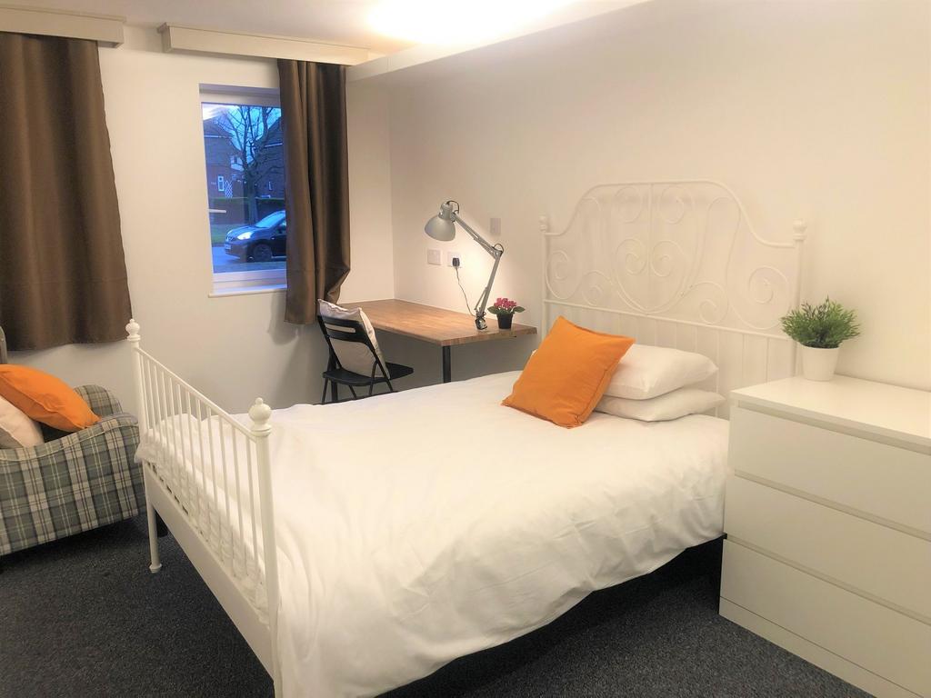 A cozy single bedroom featuring a crisp white m...