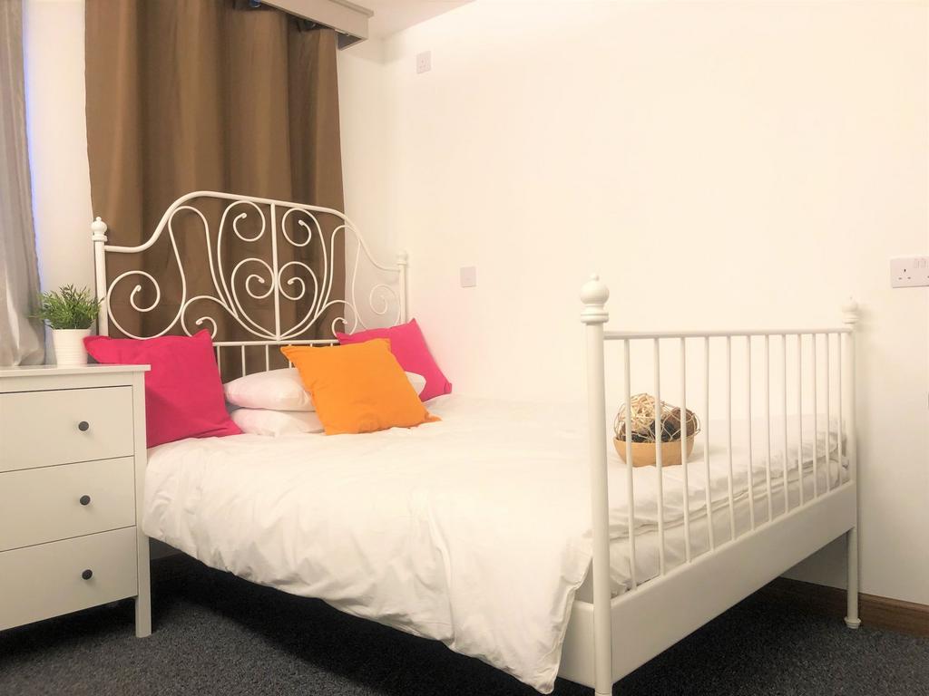 A cozy double bedroom featuring a stylish white...