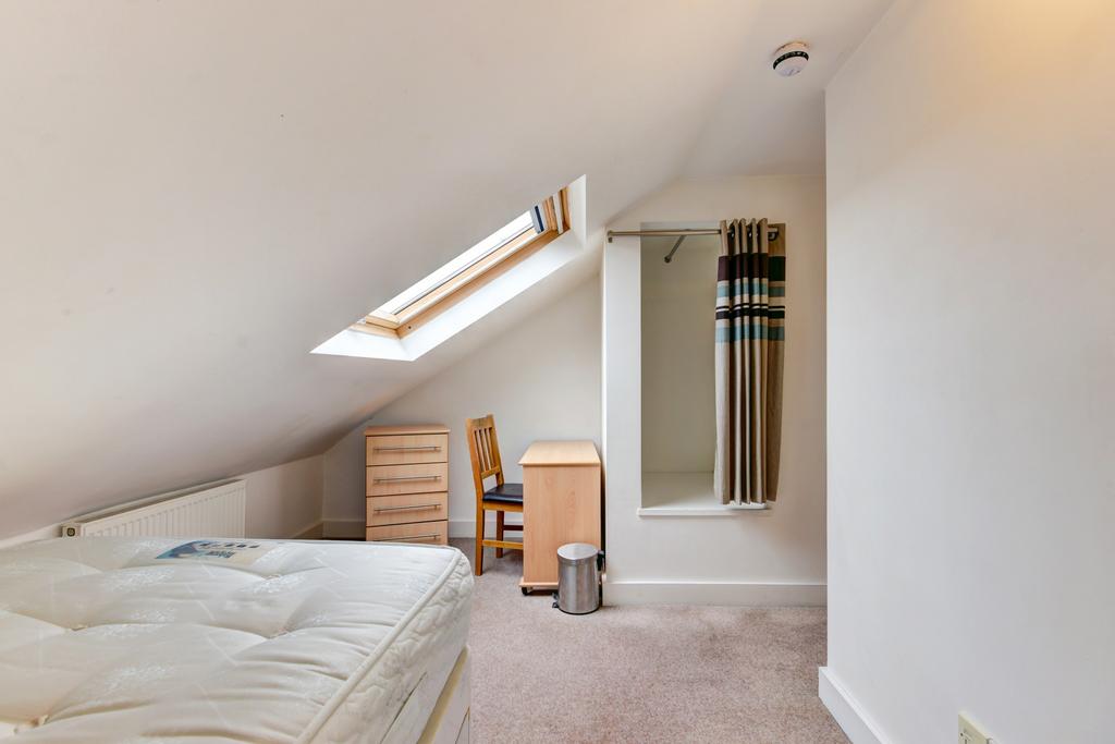 A bright and tidy bedroom with a sloped ceiling...