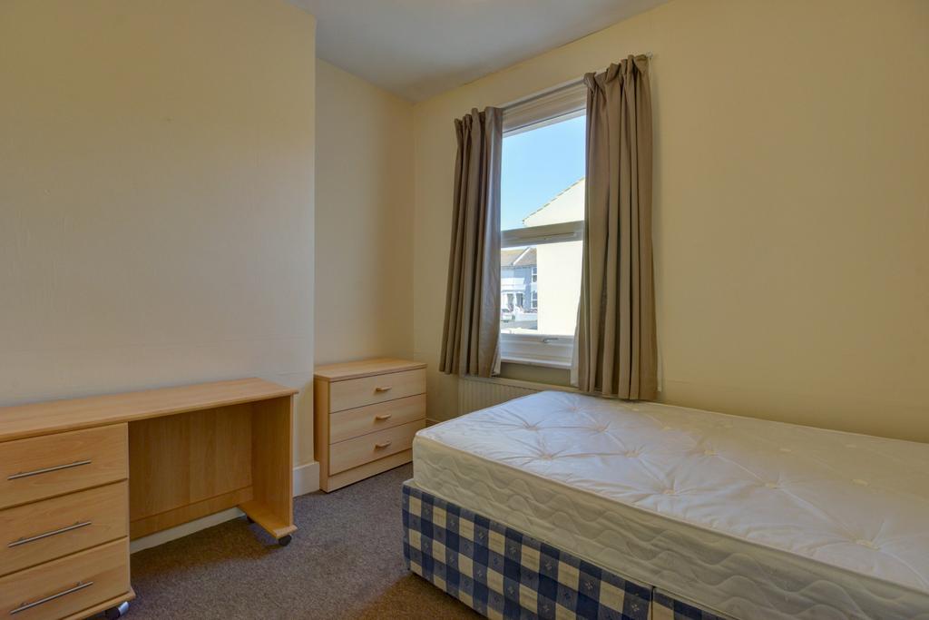 A simple student bedroom featuring a double bed...