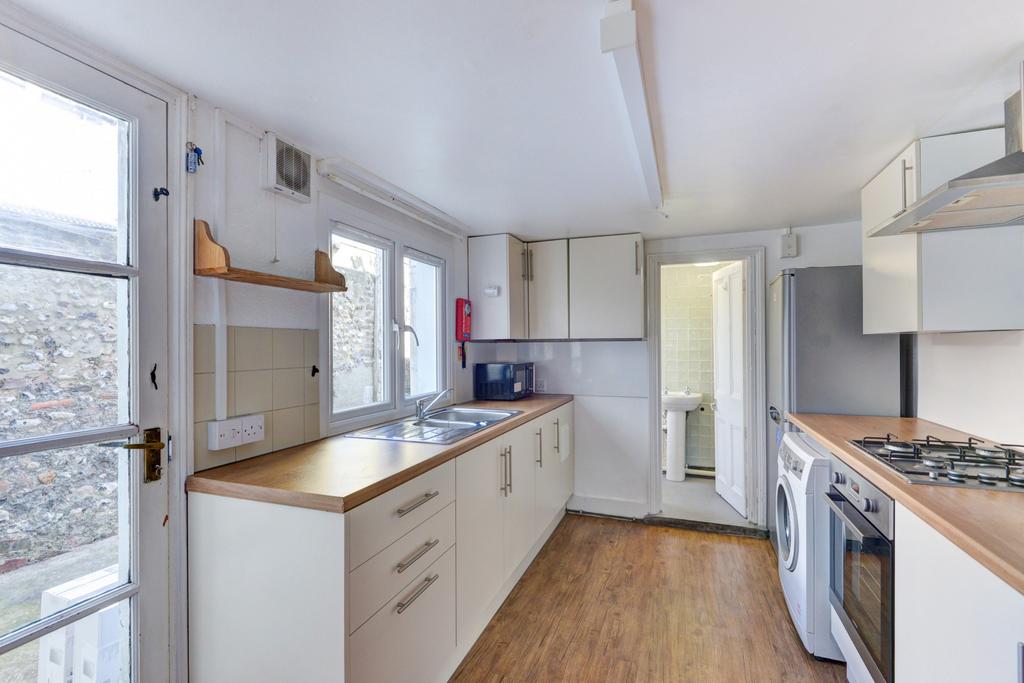 Bright galley kitchen with white cabinetry, woo...