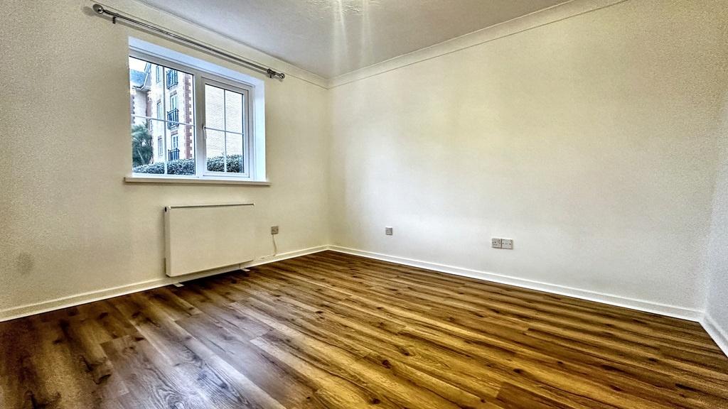 Bright, freshly painted bedroom with warm wood-...