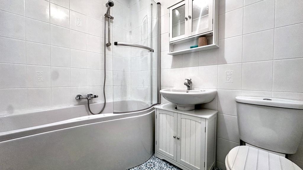 Bright, modern bathroom with a curved shower-ov...