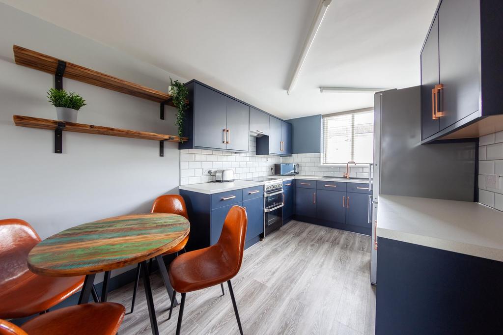 Bright modern kitchen with navy cabinetry, copp...