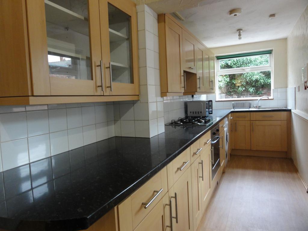 Bright galley kitchen with a long black granite...