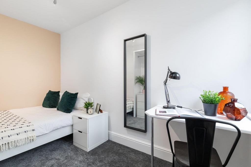 Bright, neatly furnished bedroom with a comfort...